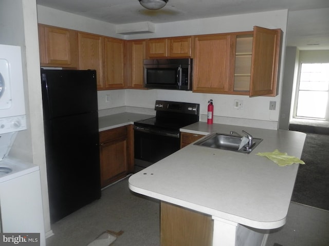 kitchen with black appliances, a sink, a peninsula, estacked washer and dryer, and glass insert cabinets