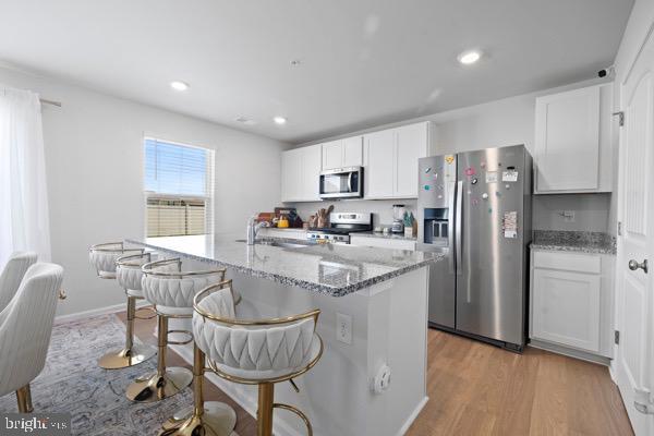 1638 Terrapin Cir, Cambridge, MD 21613 - kitchen featuring stainless steel appliances, white cabinets, light stone countertops, a kitchen breakfast bar, and recessed lighting