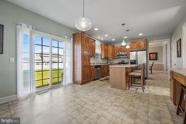 99 Topaz Ln, Camden Wyoming, DE 19934 - kitchen featuring appliances with stainless steel finishes, light countertops, a kitchen island, a breakfast bar, and pendant lighting