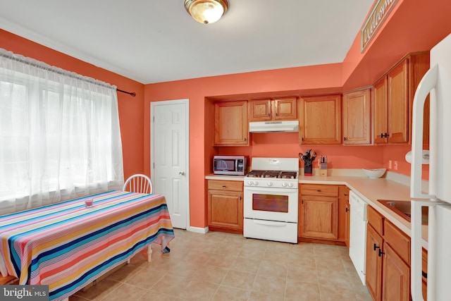 kitchen featuring white appliances, light countertops, under cabinet range hood, light tile patterned flooring, and baseboards