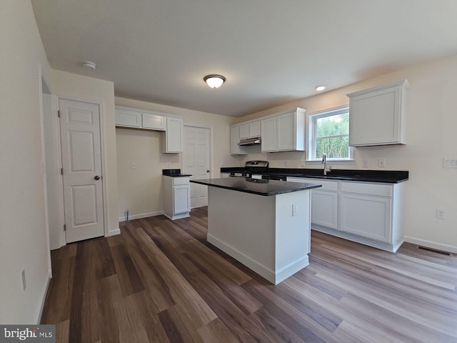 213 Newport Rd, Millville, NJ 08332 - kitchen with stainless steel gas range oven, under cabinet range hood, dark countertops, white cabinetry, and a kitchen island