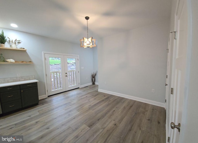 unfurnished dining area featuring french doors, a chandelier, light wood-type flooring, baseboards, and recessed lighting