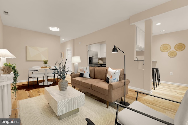 living room with light wood-type flooring, baseboards, and recessed lighting