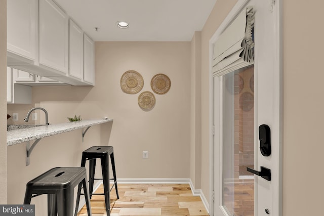 corridor featuring light wood-type flooring, recessed lighting, and baseboards