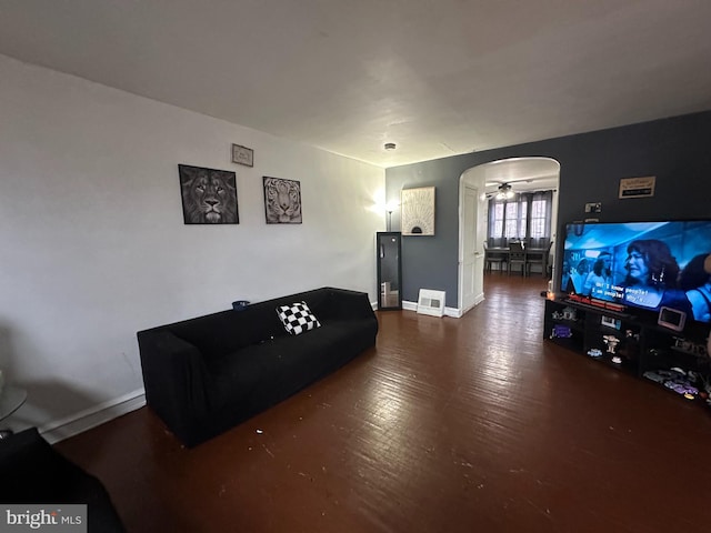 living room with arched walkways, baseboards, and wood finished floors