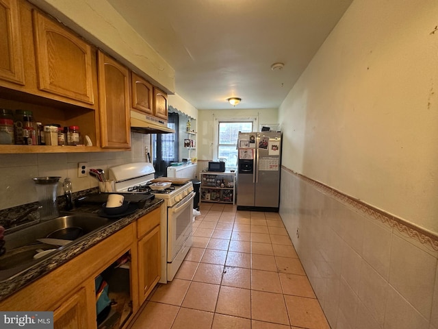 kitchen featuring stainless steel fridge, white range with gas stovetop, open shelves, dark countertops, and under cabinet range hood