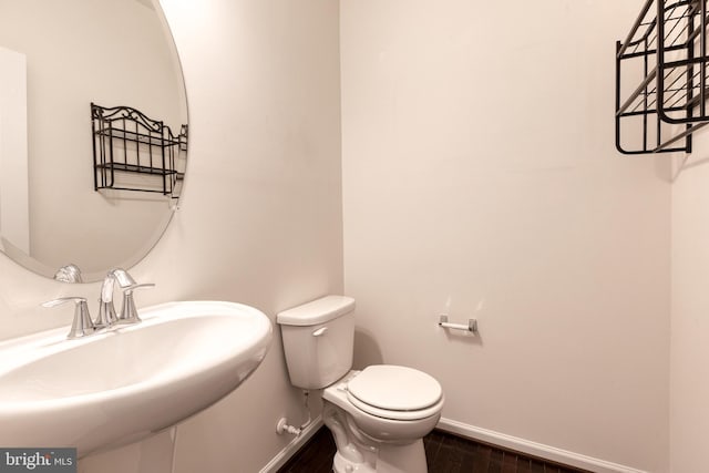 bathroom featuring a sink, baseboards, toilet, and wood finished floors