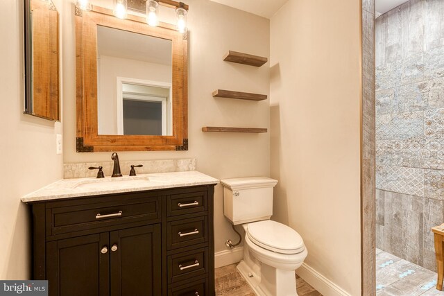 bathroom with toilet, a walk in shower, vanity, and baseboards