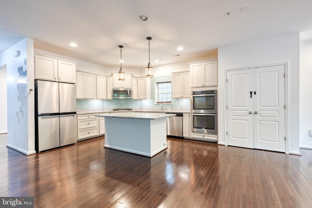kitchen with stainless steel appliances, backsplash, a kitchen island, dark wood finished floors, and recessed lighting