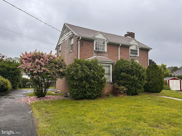 view of side of property with brick siding, a shed, and a lawn