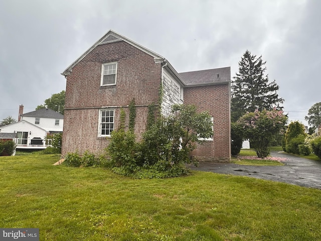 view of home's exterior with brick siding and a lawn