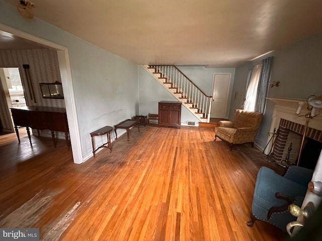 living area with stairs, wood finished floors, a fireplace, and baseboards