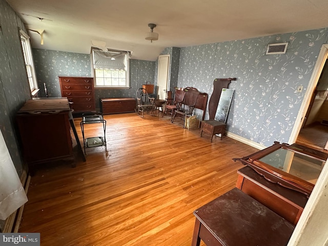 living area with wallpapered walls and wood finished floors