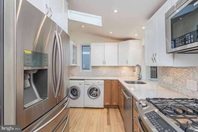 1616 S Oakland St, Arlington, VA 22204 - kitchen featuring appliances with stainless steel finishes, independent washer and dryer, a skylight, a sink, and light wood-style flooring