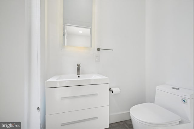 bathroom with toilet, vanity, and baseboards