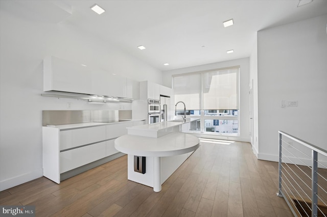 kitchen featuring modern cabinets, white cabinetry, light countertops, and stainless steel double oven