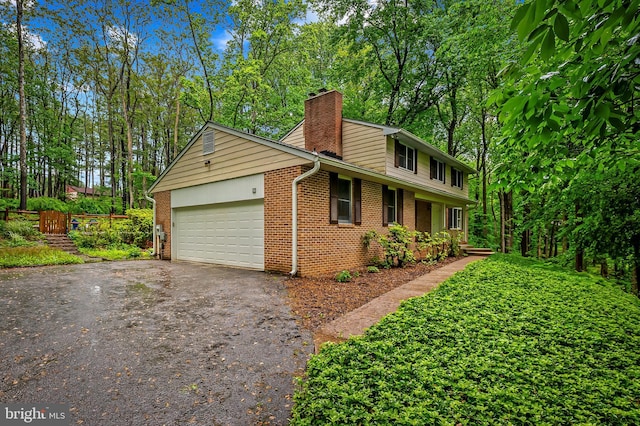 view of front of property featuring driveway, a garage, brick siding, and a chimney