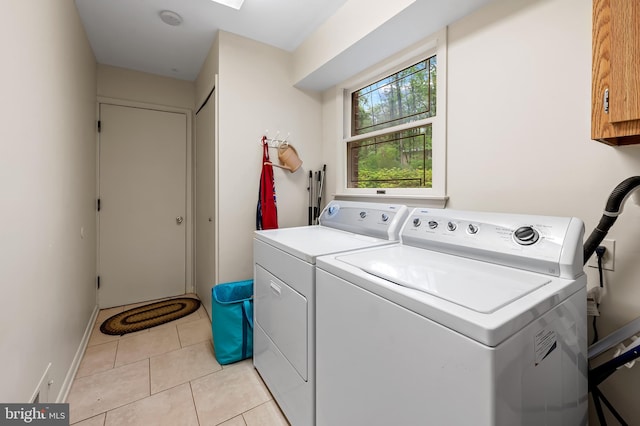 laundry room featuring cabinet space, separate washer and dryer, light tile patterned floors, and baseboards