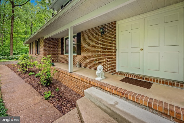 entrance to property with a porch and brick siding