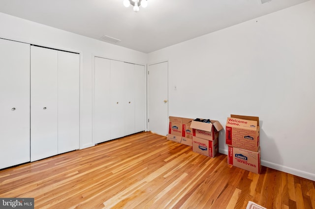 unfurnished bedroom with two closets and light wood-style floors