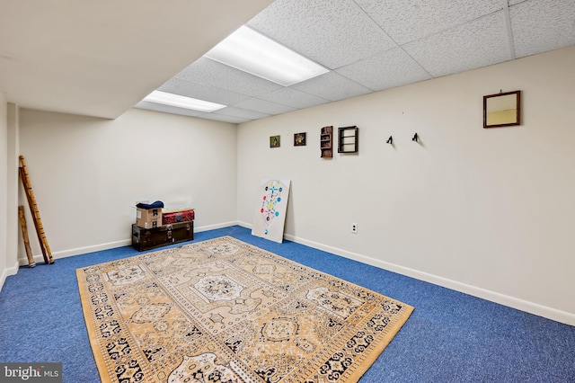 finished basement featuring carpet flooring, a drop ceiling, and baseboards