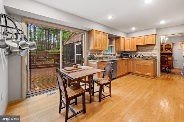 kitchen featuring dishwasher, light wood finished floors, decorative backsplash, a sink, and recessed lighting