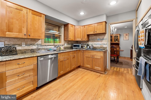kitchen with dishwasher, light wood finished floors, decorative backsplash, light stone countertops, and gas stovetop