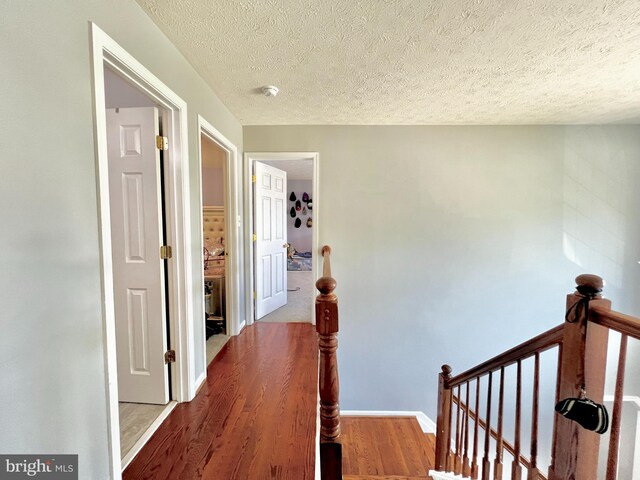 10400 Markby Ct, White Plains, MD 20695 - hall featuring an upstairs landing, wood finished floors, a textured ceiling, and baseboards