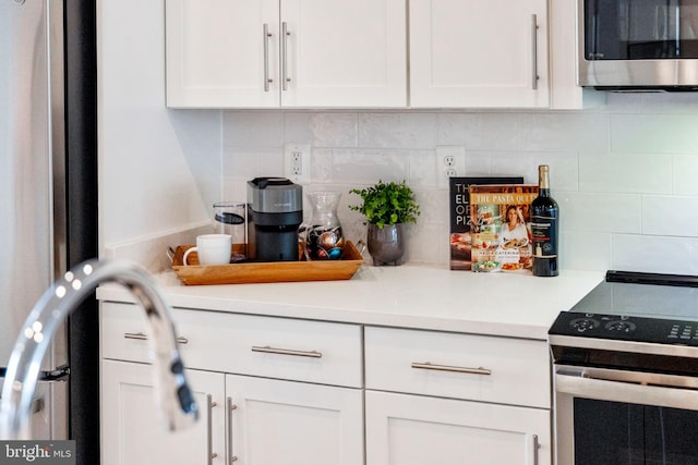 kitchen with appliances with stainless steel finishes, white cabinetry, light countertops, and backsplash