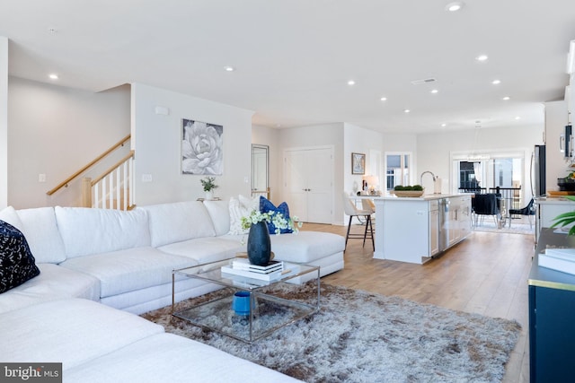 living area featuring recessed lighting, light wood-style flooring, and stairs