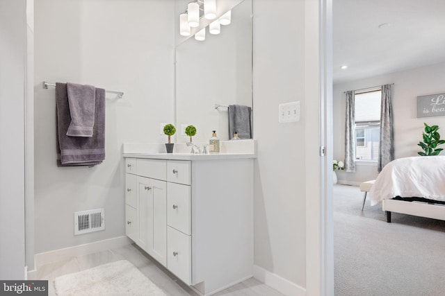 ensuite bathroom with baseboards, vanity, and a chandelier