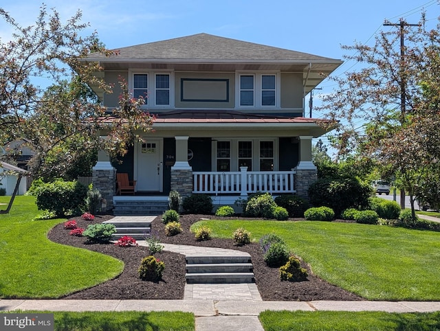 traditional style home featuring covered porch, stone siding, a front lawn, a standing seam roof, and metal roof