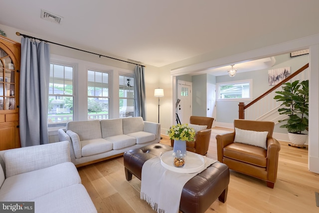 living area featuring light wood finished floors, stairs, and baseboards