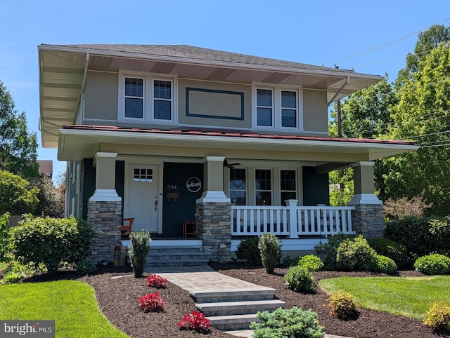 american foursquare style home featuring a porch, stone siding, and a shingled roof