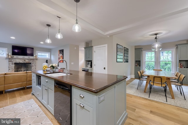 kitchen with a sink, dark countertops, black appliances, light wood finished floors, and open floor plan