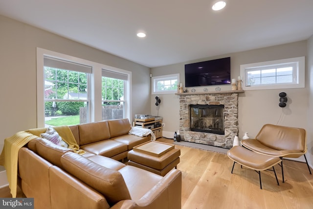 living area with a stone fireplace, wood finished floors, and recessed lighting