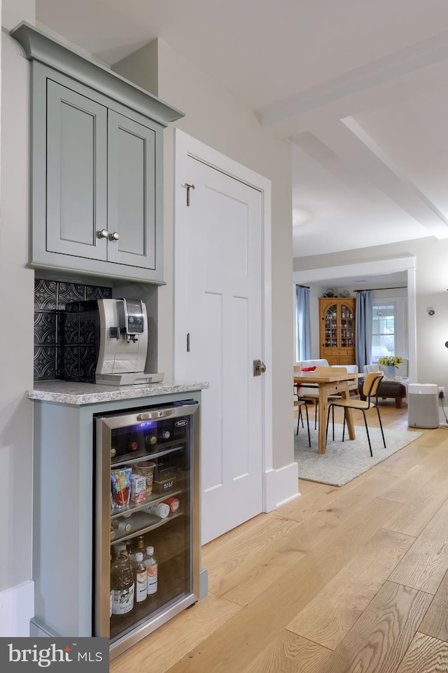 bar with wine cooler and light wood-style flooring