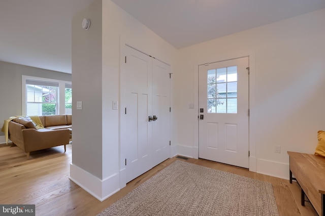 foyer entrance with light wood-style flooring and baseboards