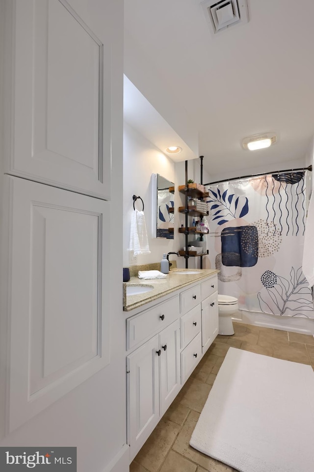 bathroom with toilet, double vanity, and curtained shower