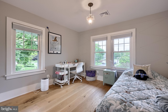 bedroom with light wood finished floors, baseboards, and an office area