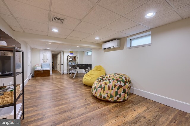sitting room featuring a wall mounted AC, wood finished floors, baseboards, a paneled ceiling, and recessed lighting