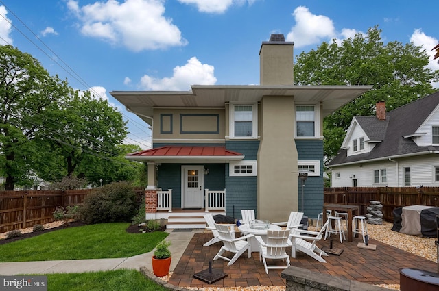 back of property with a chimney, a standing seam roof, a patio area, and metal roof