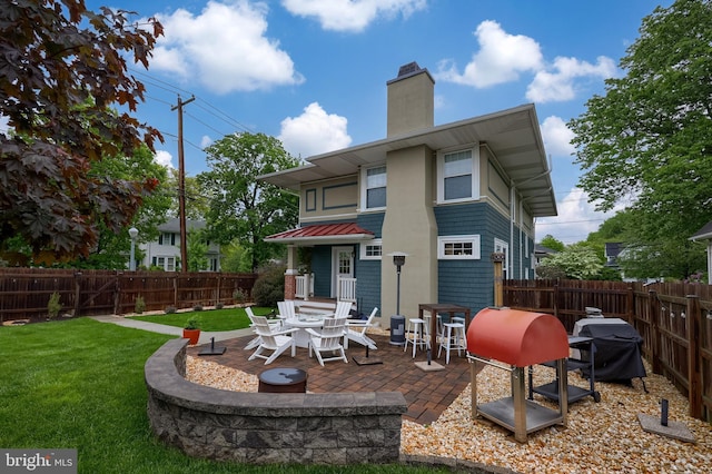 back of house featuring a patio, a chimney, a standing seam roof, and metal roof