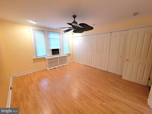 unfurnished bedroom featuring crown molding, light wood-style floors, radiator, baseboards, and a ceiling fan