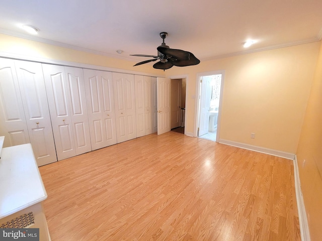 unfurnished bedroom featuring light wood-style floors, crown molding, baseboards, ensuite bathroom, and a ceiling fan