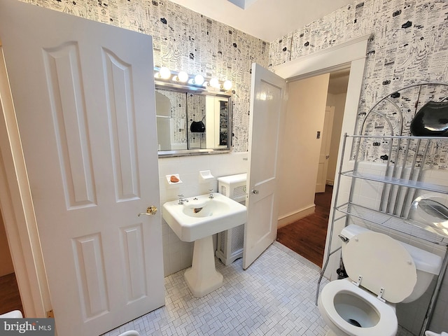 bathroom featuring toilet, tile patterned floors, and tile walls