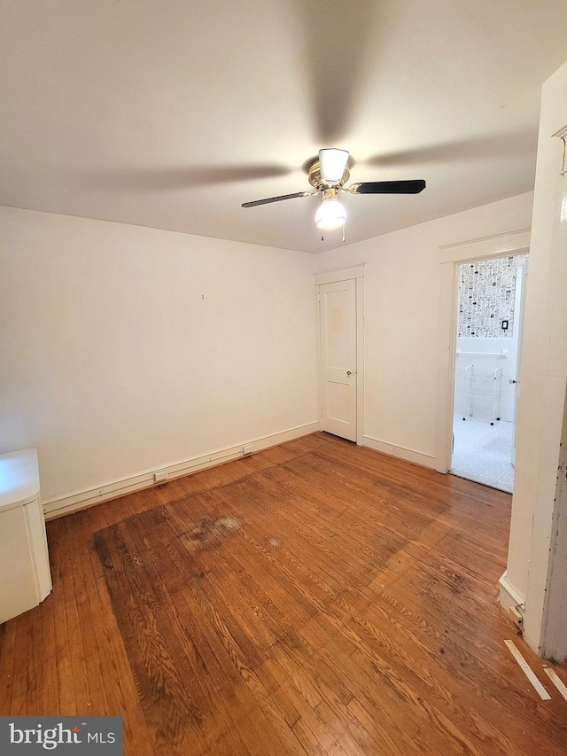 spare room with hardwood / wood-style flooring, a ceiling fan, and baseboards