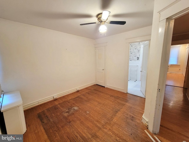unfurnished bedroom featuring wood-type flooring, baseboards, a ceiling fan, and connected bathroom