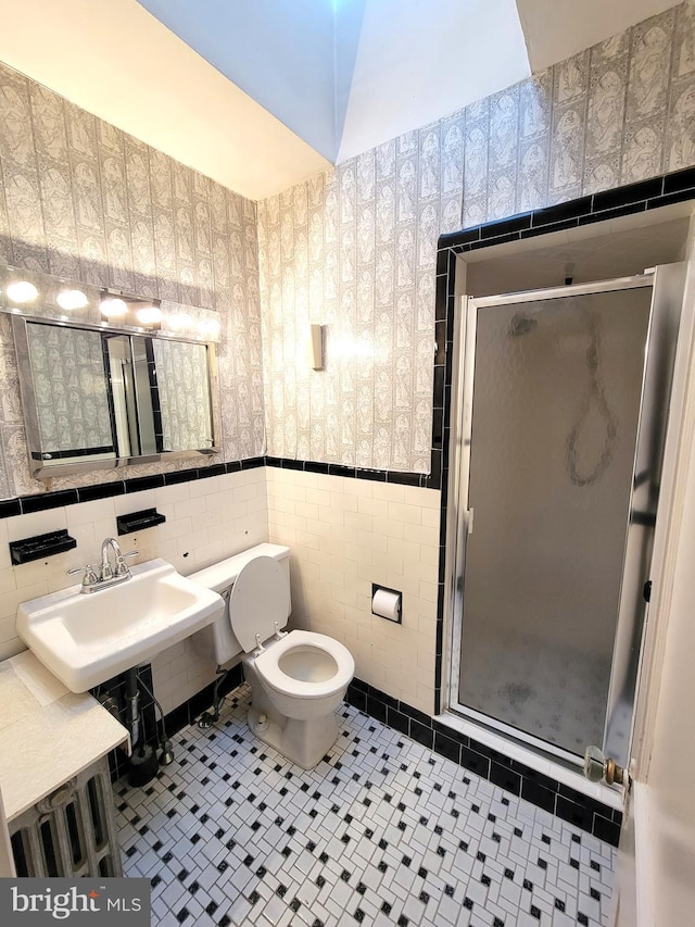 bathroom featuring wallpapered walls, tile walls, a shower stall, toilet, and tile patterned floors