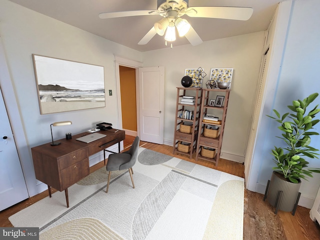 home office with wood finished floors, a ceiling fan, and baseboards